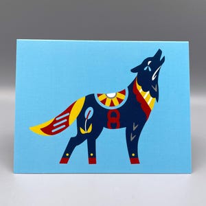 May include: A blue canvas print featuring a stylized howling wolf. The wolf is navy blue with yellow, red, and white decorative elements. The background is a solid light blue.