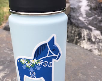 May include: A light blue reusable water bottle with a black lid and a blue and white Dala horse sticker on the side.