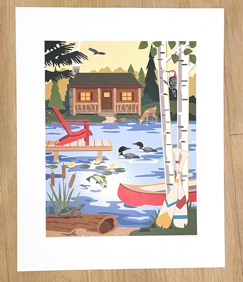 May include: A colorful print depicting a lakeside cabin scene. A red Adirondack chair sits on a wooden dock. The lake features a canoe, loons, and a turtle. Birch trees and a woodpecker are visible. The artwork evokes a sense of nature and tranquility.