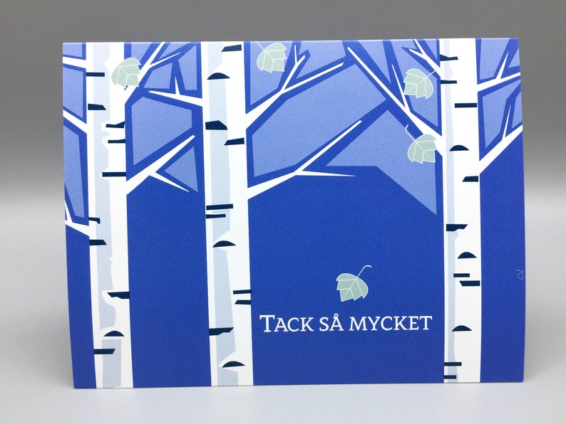 Pu&ograve; includere: Un biglietto blu e bianco con un'immagine stilizzata di betulle e il testo "TACK S&Aring; MYCKET".