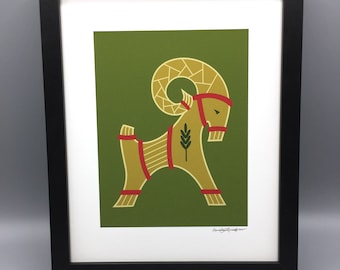 May include: A framed print of a stylised illustration of a golden goat with red accents on a green background. The artist's signature is visible in the bottom right corner.