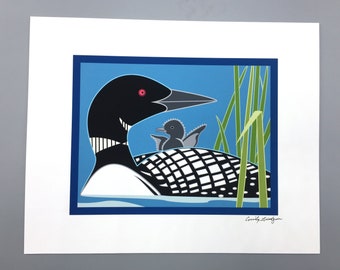 May include: A colorful illustration of a loon and its chick in a blue and green water setting. The loon is black and white with a red eye. The chick is gray with a black eye. The background is blue with green reeds.