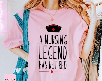 May include: A pink t-shirt with a black graphic that says "A Nursing Legend Has Retired" with a red heart and a red cross on a white nurse's cap.