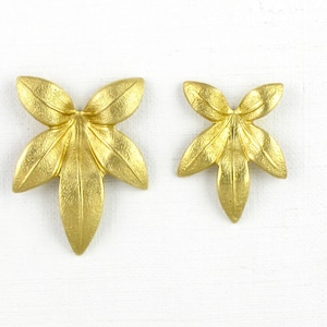 May include: Two gold-colored metal leaf-shaped ornaments. The larger ornament has five leaves and the smaller ornament has four leaves.