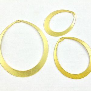 May include: Three gold metal oval-shaped hoops of different sizes. The hoops are smooth and have a shiny finish.