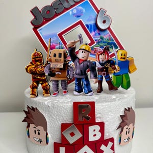 Puede incluir: Adorno para tarta con personajes de Roblox y el nombre "Josua" y el n&uacute;mero "6". La tarta est&aacute; decorada con bloques rojos que deletrean "ROBLOX" y recortes de personajes. Los personajes incluyen un caballero, un robot y otros avatares de Roblox.