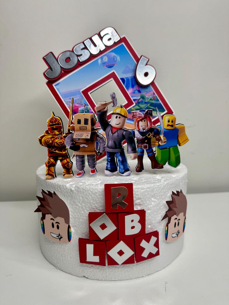 Puede incluir: Una tarta de cumplea&ntilde;os con tem&aacute;tica de Roblox con un adorno decorativo con el nombre "Josua" y el n&uacute;mero "6". La tarta est&aacute; adornada con figuras de personajes de Roblox y el logotipo de Roblox en rojo y blanco.