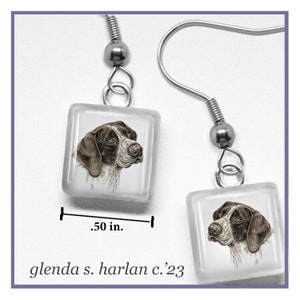 May include: A pair of silver dangle earrings with a square glass charm featuring a black and white illustration of a German Shorthaired Pointer dog. The charm measures 0.50 inches.