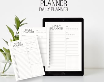 May include: Two black and white daily planner pages with the text "DAILY PLANNER" at the top. The pages are on a white surface with a green plant in a glass vase.