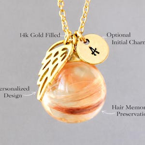 Pode incluir: Colar banhado a ouro com um pingente contendo preserva&ccedil;&atilde;o memorial de cabelo. O pingente &eacute; um globo transparente com mechas de cabelo dentro. Inclui um pingente de asa dourada e um pingente redondo com a inicial "A".