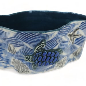 May include: A blue and white ceramic bowl with a wavy design and a sea turtle, starfish, and coral accents.