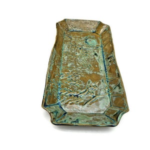 May include: A rectangular ceramic serving tray with a green and gold glaze. The tray has a raised design of leaves and branches.