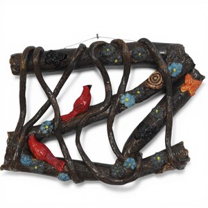 May include: A decorative wall hanging shaped like the letter Z, crafted to resemble dark brown tree branches with intertwined vines. The piece features two bright red cardinal birds, several small blue flowers with yellow centres, a snail, and an orange butterfly.