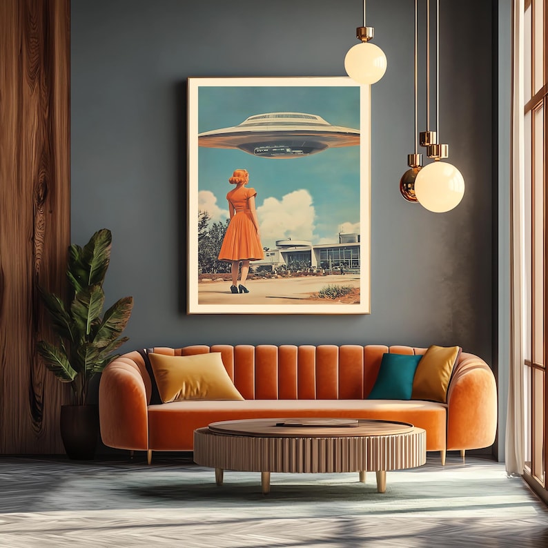 Może przedstawiać: Ilustracja w stylu retro kobiety w jasno pomarańczowej sukience stojącej przed budynkiem, patrzącej w g&oacute;rę na latający spodek. Obraz jest oprawiony i wisi na ścianie nad brązową kanapą z pomarańczowymi poduszkami.