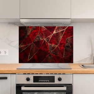 May include: A modern kitchen with a stainless steel oven and stovetop. The backsplash is a red and gold geometric pattern.