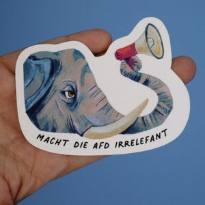 Könnte beinhalten: Ein weißer Aufkleber mit einer Cartoon-Illustration eines Elefanten, der ein Megaphon hält. Der Rüssel des Elefanten ist um das Megaphon gewickelt. Der Text "Macht die AfD irrelefant" ist in Schwarz am unteren Rand des Aufklebers geschrieben.