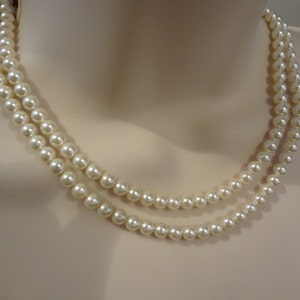 May include: A double strand of white faux pearl necklace. The pearls are round and smooth.
