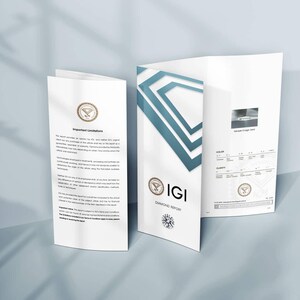 May include: Three white IGI Diamond Report brochures with teal geometric designs and text. The brochures are open, displaying text and a diamond image. The IGI logo and a diamond graphic are visible. The brochures are on a light blue surface.