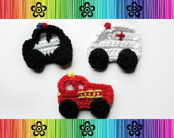 May include: Three crocheted toy vehicles: a black and white police car, a white ambulance with a red cross, and a red fire truck with yellow ladders.