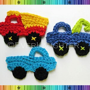 May include: Three crocheted toy trucks in red, blue, and turquoise. The red truck has a yellow bed. The blue truck has a green hook. The turquoise truck has a black windshield.