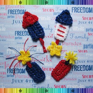 May include: Crocheted red, white, and blue firework ornaments with yellow stars and a blue background with the words "FREEDOM" and "JULY 4TH" repeated.
