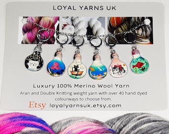 May include: A set of six decorative stitch markers, each shaped like a lightbulb with a different whimsical design, including a cat, octopus, and fish. The markers are attached to a silver chain. The card behind the markers reads "LOYAL YARNS UK".