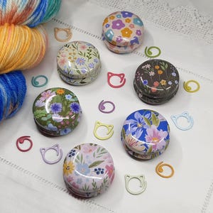 Floral stitch marker tins with painted metal stitch markers. Knitting and crochet notions and accessories.