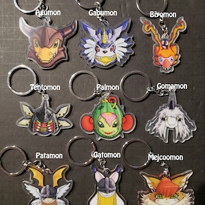 Op de afbeelding: Negen transparante acryl sleutelhangers met verschillende Digimon-personages. De personages zijn Agumon, Gabumon, Biyomon, Tentomon, Palmon, Gomamon, Patamon, Gatomon en Meicoomon.