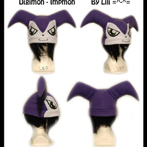 May include: Purple and white Impmon hat with long ears. The hat is on a mannequin head with black hair. The text "Digimon - Impmon" and "By Lili =^_^=" is visible in the image.
