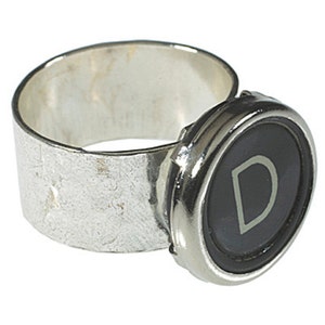 May include: A silver ring with a black typewriter key featuring the letter "D" in white.