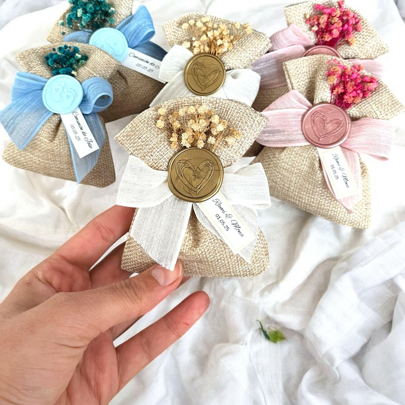May include: Small burlap bags with a heart-shaped wax seal and a ribbon. The bags are filled with dried flowers and have a personalized tag with the date and names "Romeo & Maria 01.01.23".