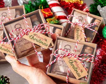 Può includere: Piccole confezioni regalo con caffè turco e una piccola bottiglia di vetro, legate con spago rosso e bianco. Ogni scatola ha un'etichetta con la scritta "Merry Christmas". Decorazioni natalizie.
