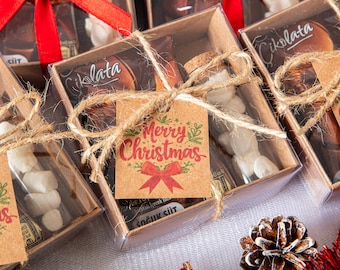 Può includere: Diverse piccole scatole regalo legate con spago e nastro rosso, ognuna contenente dolcetti. Un'etichetta con "Merry Christmas" è attaccata a una scatola. Le scatole sono piene di cioccolatini e marshmallow, perfette per i regali natalizi.