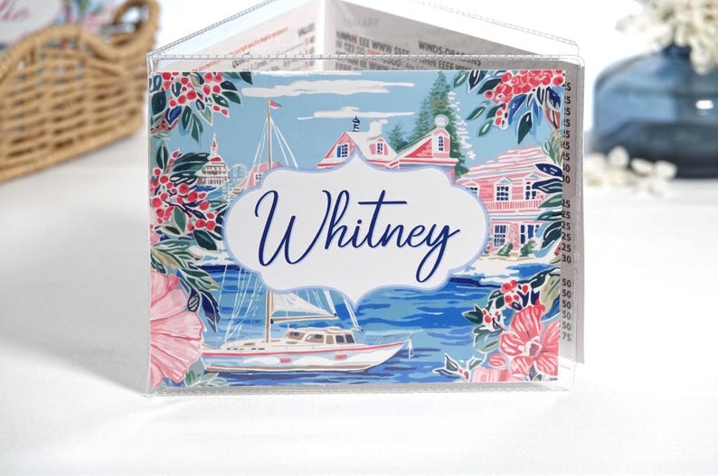 Personalized blue and pink coastal mahjong card cover featuring a sailboat harbor scene, waterfront cottage, floral accents, and optional clear sleeve for Large NMJL cards