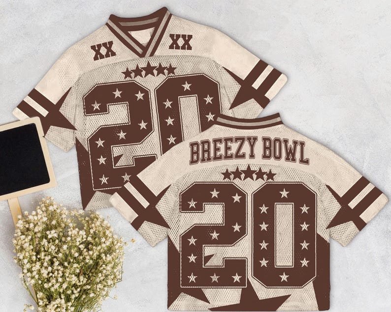 Pu&ograve; includere: Due maglie da football beige e marroni con il numero 20 e dettagli a stella. Una maglia ha la scritta "Breezy Bowl" sul retro. Le maglie hanno un aspetto vintage e usurato.