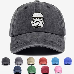 May include: A black denim baseball cap featuring a white embroidered image of a Star Wars Stormtrooper helmet. The cap is available in a range of colours.