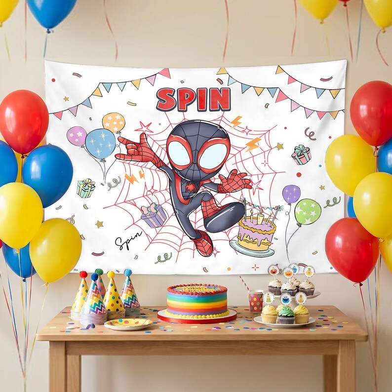 May include: A white party backdrop featuring a cartoon character in a black and red suit, a spiderweb, colorful balloons, gift boxes, and a birthday cake. The text SPIN is printed in red at the top. A rainbow cake and cupcakes sit on a table.