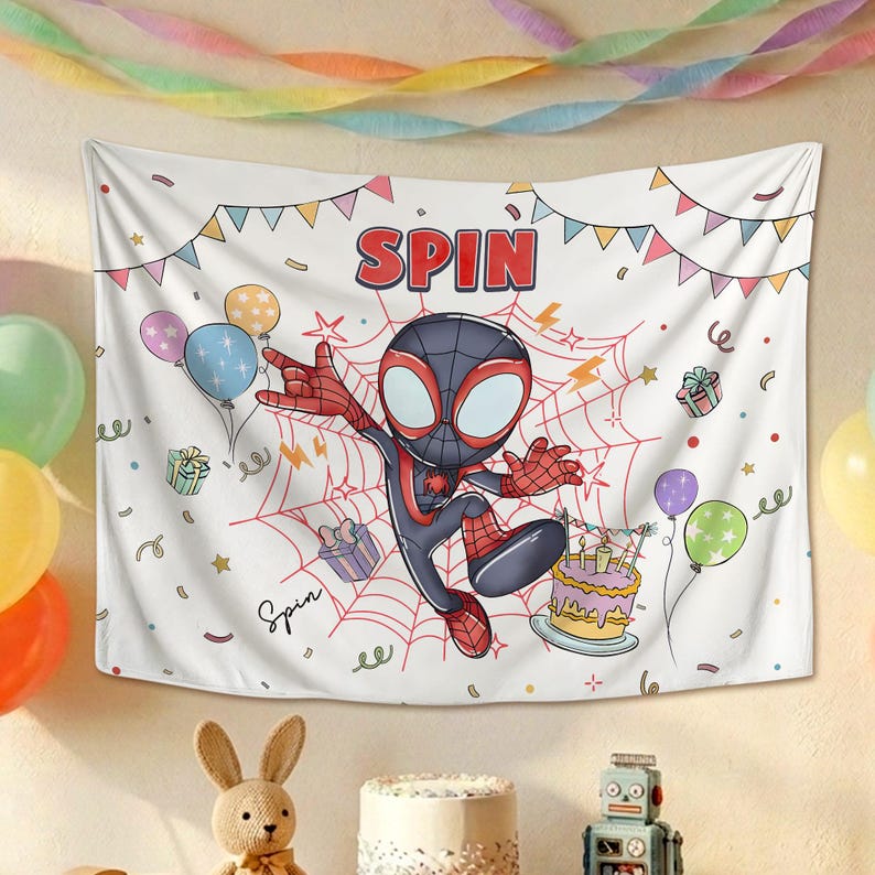 May include: A white fabric wall tapestry featuring a cartoon character in a black and red suit with large eyes, centered on a red spiderweb. The text SPIN appears at the top, surrounded by colorful balloons, gift boxes, a birthday cake, and bunting.