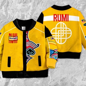 May include: A yellow bomber jacket with black detailing, displaying the word "RUMI" on the back and front. The jacket has a colourful design on the sleeves and front, with the text "Rrrrrrumi" on the front.