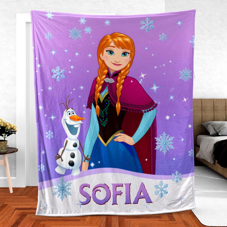 May include: A purple fleece blanket featuring a graphic illustration of Anna from Frozen with braided hair and a maroon cape, standing next to Olaf the snowman. The background is decorated with light blue snowflakes and stars, with the name SOFIA printed.