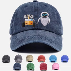 May include: A blue denim baseball cap with an embroidered image of Wall-E and Eve from the animated film Wall-E. The cap has a curved brim and an adjustable strap.