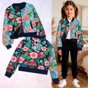 May include: A floral bomber jacket featuring a vibrant pattern of pink hibiscus flowers, green leaves, and orange foliage against a navy blue and light blue background. The jacket has a black zipper, navy blue cuffs, and a white emblem on the back.