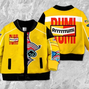 May include: A yellow bomber jacket with black accents, featuring the text "DUMI Rrrrrrrrumi" in red and white. The jacket has a colorful design on the sleeves and a black collar and cuffs. The jacket is shown from the front and back.