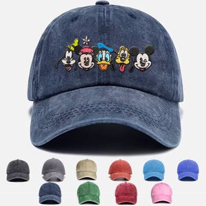 May include: A blue denim baseball cap featuring an embroidered design of Mickey Mouse, Minnie Mouse, Donald Duck, Goofy, and Pluto. The characters are smiling and have their signature features.