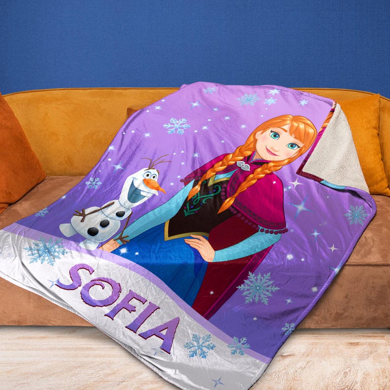 May include: A purple fleece blanket featuring a printed graphic of Anna from Frozen and Olaf the snowman. The design includes light blue snowflakes and the name SOFIA in large purple letters at the bottom. The blanket has a white sherpa lining.