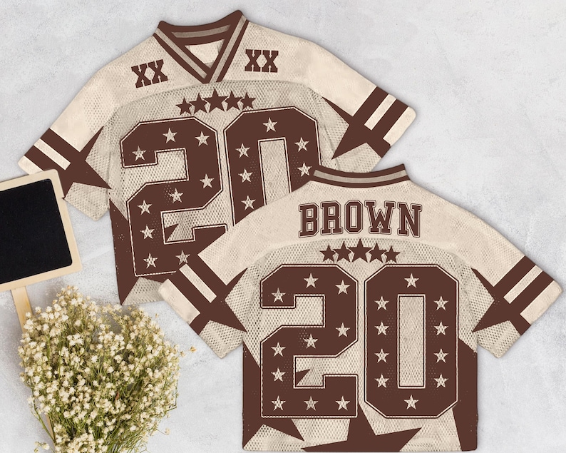 Pu&ograve; includere: Due maglie da football beige e marroni con il numero 20 e dettagli a stella. Una maglia ha il nome "BROWN" sul retro. Le maglie hanno un design a rete e strisce marroni sulle maniche.