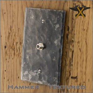 May include: A hammered metal wall plate with a single coaxial cable connector. The plate has a rough, textured surface and is mounted on a wooden wall.