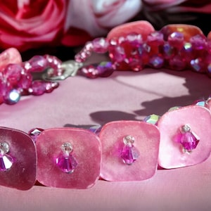 May include: A pink and iridescent beaded necklace with square pink shell-like beads and pink crystal accents.