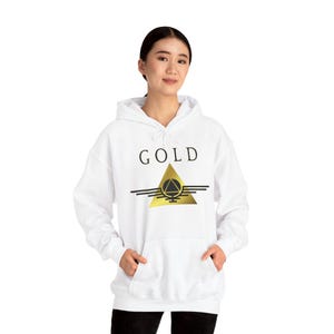 May include: White hooded sweatshirt with the word "GOLD" in black block letters above a gold triangle design with horizontal lines. The sweatshirt has a front pocket and a drawstring hood.