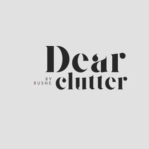 Puede incluir: Logotipo en blanco y negro con el texto "Dear clutter" y las palabras "by rusne" debajo.